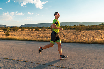 Image showing Triathlete in professional gear running early in the morning, preparing for a marathon, dedication to sport and readiness to take on the challenges of a marathon.