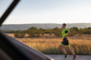 Image showing Triathlete in professional gear running early in the morning, preparing for a marathon, dedication to sport and readiness to take on the challenges of a marathon.