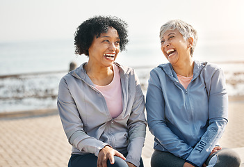 Image showing Senior women, laughing and beach with friends, training and sitting in summer outdoor. Exercise, break and mature female in the morning with funny joke and workout for wellness and health by sea