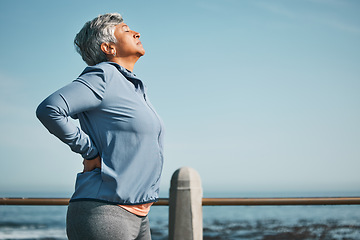 Image showing Tired, running and senior woman pain from back ache by the ocean for fitness, exercise and workout. Runner, person with sport outdoor on beach with muscle strain and athlete injury on mockup space