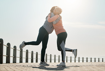 Image showing Running, hug and women by sea and ocean with love and care for fitness and exercise. Athlete, wellness and female friends on a beach promenade with motivation, embrace and smile from runner target