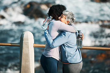 Image showing Running, hug and sport women by sea and ocean with training and happy for fitness and exercise. Athlete, wellness and mature person and friend on promenade with motivation, embrace and woman smile