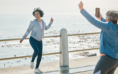 Image showing Phone, friends picture and senior woman smile at beach with silly pose at sea for fitness. Exercise, mobile and photo for social media post on a ocean promenade walk for workout and friendship