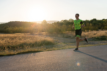 Image showing Triathlete in professional gear running early in the morning, preparing for a marathon, dedication to sport and readiness to take on the challenges of a marathon.