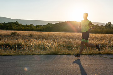 Image showing Triathlete in professional gear running early in the morning, preparing for a marathon, dedication to sport and readiness to take on the challenges of a marathon.