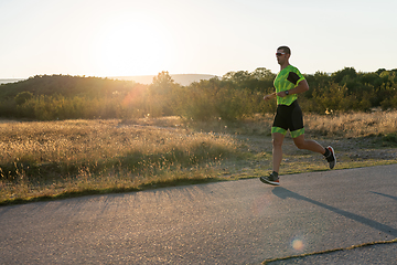 Image showing Triathlete in professional gear running early in the morning, preparing for a marathon, dedication to sport and readiness to take on the challenges of a marathon.