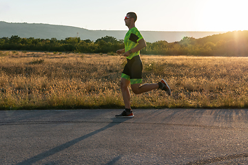 Image showing Triathlete in professional gear running early in the morning, preparing for a marathon, dedication to sport and readiness to take on the challenges of a marathon.