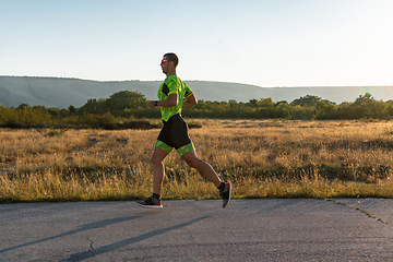 Image showing Triathlete in professional gear running early in the morning, preparing for a marathon, dedication to sport and readiness to take on the challenges of a marathon.