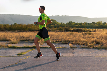 Image showing Triathlete in professional gear running early in the morning, preparing for a marathon, dedication to sport and readiness to take on the challenges of a marathon.