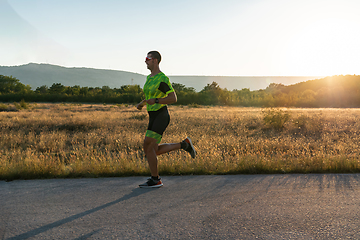 Image showing Triathlete in professional gear running early in the morning, preparing for a marathon, dedication to sport and readiness to take on the challenges of a marathon.