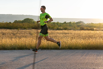 Image showing Triathlete in professional gear running early in the morning, preparing for a marathon, dedication to sport and readiness to take on the challenges of a marathon.