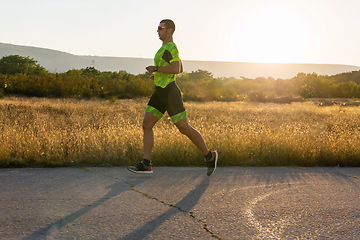 Image showing Triathlete in professional gear running early in the morning, preparing for a marathon, dedication to sport and readiness to take on the challenges of a marathon.