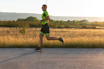 Image showing Triathlete in professional gear running early in the morning, preparing for a marathon, dedication to sport and readiness to take on the challenges of a marathon.