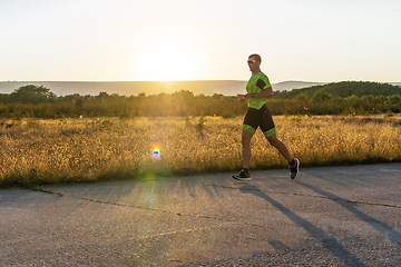 Image showing Triathlete in professional gear running early in the morning, preparing for a marathon, dedication to sport and readiness to take on the challenges of a marathon.