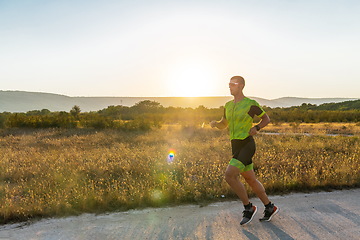 Image showing Triathlete in professional gear running early in the morning, preparing for a marathon, dedication to sport and readiness to take on the challenges of a marathon.