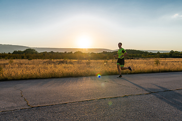 Image showing Triathlete in professional gear running early in the morning, preparing for a marathon, dedication to sport and readiness to take on the challenges of a marathon.