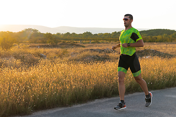 Image showing Triathlete in professional gear running early in the morning, preparing for a marathon, dedication to sport and readiness to take on the challenges of a marathon.