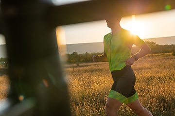 Image showing Triathlete in professional gear running early in the morning, preparing for a marathon, dedication to sport and readiness to take on the challenges of a marathon.