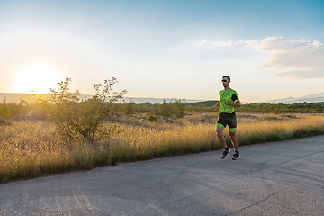 Image showing Triathlete in professional gear running early in the morning, preparing for a marathon, dedication to sport and readiness to take on the challenges of a marathon.