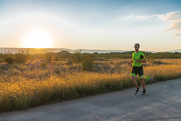 Image showing Triathlete in professional gear running early in the morning, preparing for a marathon, dedication to sport and readiness to take on the challenges of a marathon.