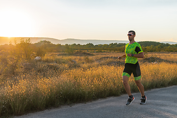 Image showing Triathlete in professional gear running early in the morning, preparing for a marathon, dedication to sport and readiness to take on the challenges of a marathon.