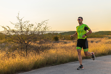 Image showing Triathlete in professional gear running early in the morning, preparing for a marathon, dedication to sport and readiness to take on the challenges of a marathon.