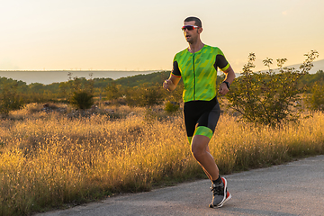 Image showing Triathlete in professional gear running early in the morning, preparing for a marathon, dedication to sport and readiness to take on the challenges of a marathon.