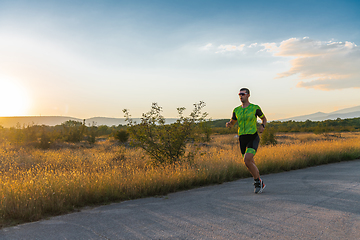 Image showing Triathlete in professional gear running early in the morning, preparing for a marathon, dedication to sport and readiness to take on the challenges of a marathon.