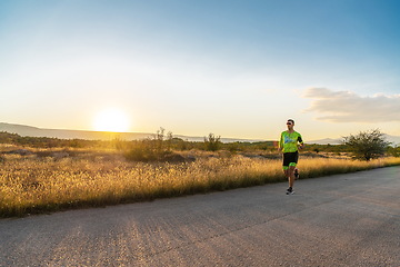 Image showing Triathlete in professional gear running early in the morning, preparing for a marathon, dedication to sport and readiness to take on the challenges of a marathon.