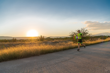 Image showing Triathlete in professional gear running early in the morning, preparing for a marathon, dedication to sport and readiness to take on the challenges of a marathon.