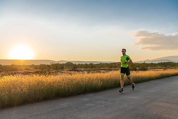 Image showing Triathlete in professional gear running early in the morning, preparing for a marathon, dedication to sport and readiness to take on the challenges of a marathon.