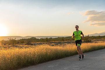 Image showing Triathlete in professional gear running early in the morning, preparing for a marathon, dedication to sport and readiness to take on the challenges of a marathon.