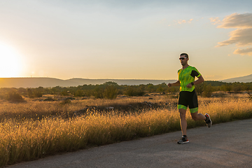 Image showing Triathlete in professional gear running early in the morning, preparing for a marathon, dedication to sport and readiness to take on the challenges of a marathon.