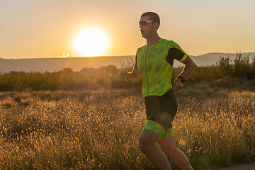 Image showing Triathlete in professional gear running early in the morning, preparing for a marathon, dedication to sport and readiness to take on the challenges of a marathon.