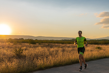 Image showing Triathlete in professional gear running early in the morning, preparing for a marathon, dedication to sport and readiness to take on the challenges of a marathon.