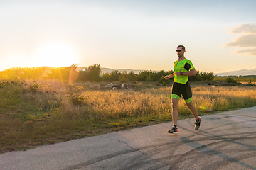 Image showing Triathlete in professional gear running early in the morning, preparing for a marathon, dedication to sport and readiness to take on the challenges of a marathon.