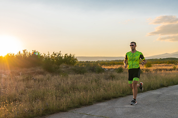 Image showing Triathlete in professional gear running early in the morning, preparing for a marathon, dedication to sport and readiness to take on the challenges of a marathon.