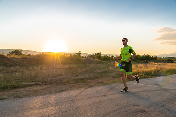 Image showing Triathlete in professional gear running early in the morning, preparing for a marathon, dedication to sport and readiness to take on the challenges of a marathon.