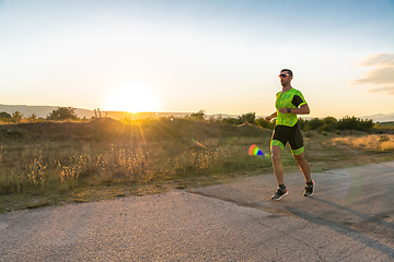 Image showing Triathlete in professional gear running early in the morning, preparing for a marathon, dedication to sport and readiness to take on the challenges of a marathon.