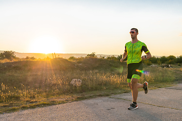 Image showing Triathlete in professional gear running early in the morning, preparing for a marathon, dedication to sport and readiness to take on the challenges of a marathon.