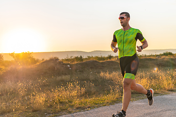 Image showing Triathlete in professional gear running early in the morning, preparing for a marathon, dedication to sport and readiness to take on the challenges of a marathon.