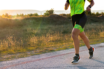 Image showing Triathlete in professional gear running early in the morning, preparing for a marathon, dedication to sport and readiness to take on the challenges of a marathon.