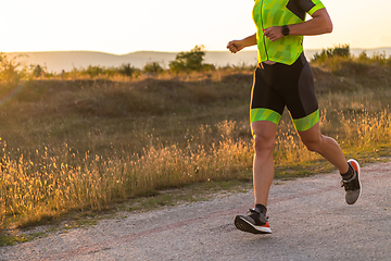 Image showing Triathlete in professional gear running early in the morning, preparing for a marathon, dedication to sport and readiness to take on the challenges of a marathon.