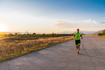 Image showing Triathlete in professional gear running early in the morning, preparing for a marathon, dedication to sport and readiness to take on the challenges of a marathon.