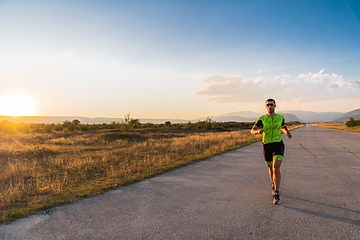 Image showing Triathlete in professional gear running early in the morning, preparing for a marathon, dedication to sport and readiness to take on the challenges of a marathon.