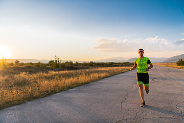 Image showing Triathlete in professional gear running early in the morning, preparing for a marathon, dedication to sport and readiness to take on the challenges of a marathon.