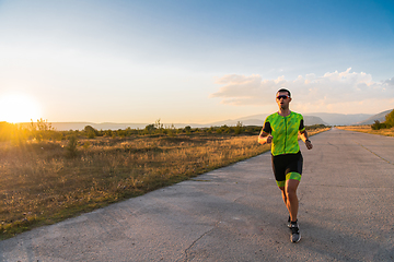 Image showing Triathlete in professional gear running early in the morning, preparing for a marathon, dedication to sport and readiness to take on the challenges of a marathon.