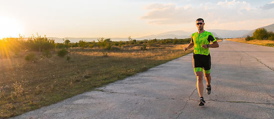 Image showing Triathlete in professional gear running early in the morning, preparing for a marathon, dedication to sport and readiness to take on the challenges of a marathon.