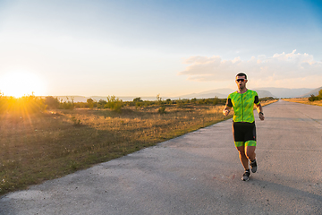 Image showing Triathlete in professional gear running early in the morning, preparing for a marathon, dedication to sport and readiness to take on the challenges of a marathon.