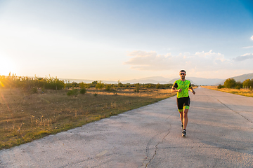 Image showing Triathlete in professional gear running early in the morning, preparing for a marathon, dedication to sport and readiness to take on the challenges of a marathon.